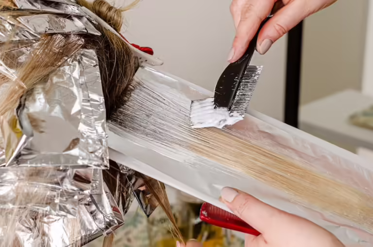 Mujer tintando un cabello con producto blanco